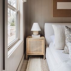 a white couch sitting next to a window in a room with wood paneled walls