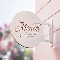 a white sign hanging from the side of a pink building that says minaa beauty land