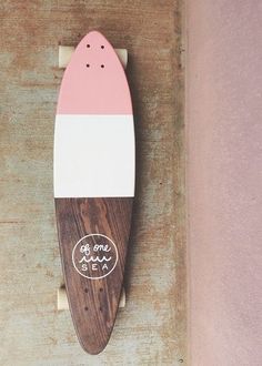 a wooden skateboard mounted to the side of a wall with pink and white stripes