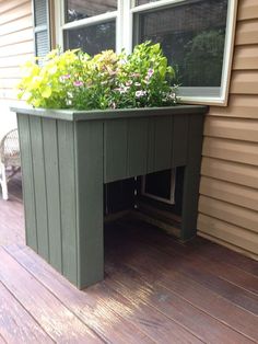 a green planter sitting on top of a wooden deck next to a window filled with flowers