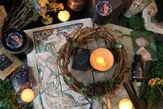 a table topped with lots of candles next to books and other items on top of it