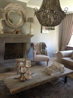 a living room filled with furniture and a chandelier hanging over the fire place