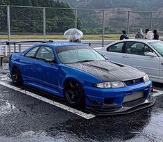 two cars parked next to each other in a parking lot with water on the ground