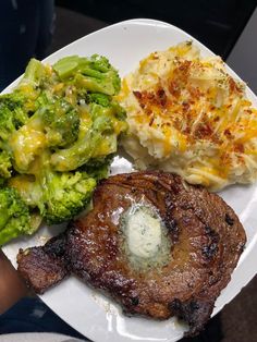 a white plate topped with meat and veggies next to mashed potatoes, broccoli