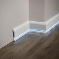 the corner of a room with wood flooring and white painted walls, has a light strip running through it