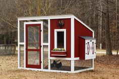 a red and white chicken coop in the woods