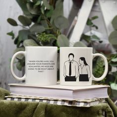 two coffee mugs sitting on top of a book