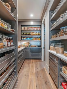 an organized pantry with lots of food in the shelves and drawers on both sides, along with wooden flooring