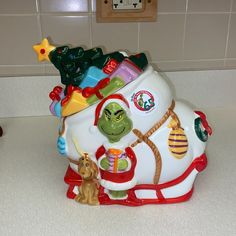 a ceramic christmas ornament sitting on top of a counter next to a clock