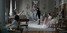 a group of women sitting around a living room next to a piano and other furniture