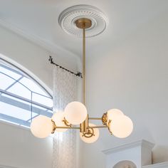 a chandelier hanging from the ceiling in a room with white walls and windows