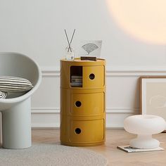 a yellow cabinet sitting next to a white chair on top of a hard wood floor