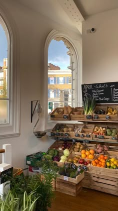 an open market with fruits and vegetables on display in front of two arched windows that look out onto the street