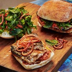 two sandwiches are sitting on a cutting board