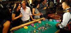 a group of people standing around a casino table