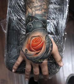 a person with a tattoo on their arm holding a rose in his hand and the other hand