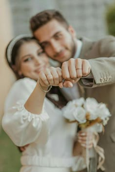 a bride and groom are posing for a wedding photo with their hands in the air