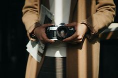 a woman holding a camera in her hands while standing next to another person's hand