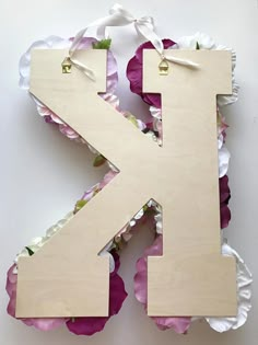 the letter k is made out of plywood and paper with pink flowers around it