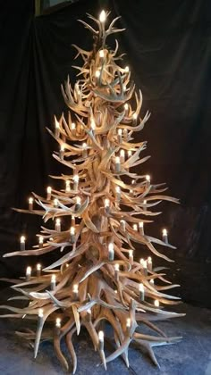 a christmas tree made out of antlers with candles on it's sides and the bottom