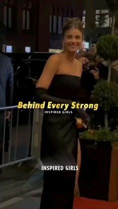 a woman in a strapless black dress standing on a red carpet and smiling at the camera