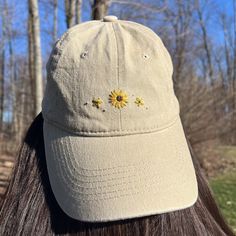 the back of a woman's head wearing a hat with sunflowers embroidered on it