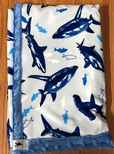 a blue and white blanket with sharks on it sitting on top of a wooden floor