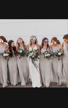 a group of women standing next to each other in dresses with sunglasses on their faces