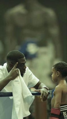 a man wiping his face while standing next to a little boy with boxing gloves on