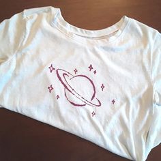 a white t - shirt with an image of saturn on it