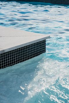 an empty swimming pool with blue water and tiled walls, as seen from the side