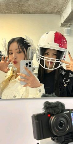 a woman taking a selfie in front of a mirror with a football helmet on