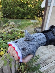 a hand holding a knitted mitt with a shark on it