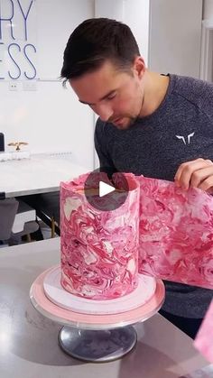 a man is decorating a cake with pink icing