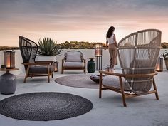 a woman standing on top of a roof next to chairs and tables filled with potted plants