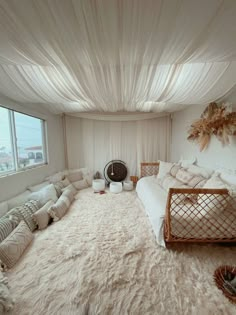 a large bed sitting in the middle of a living room next to a big window