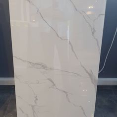 a white marble counter top in front of a black and white wall with an electrical outlet