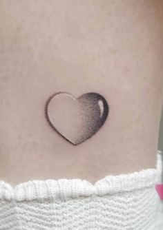 a small heart tattoo on the side of a woman's stomach is shown in black and white