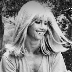 black and white photograph of a woman sitting on a bench with her hair blowing in the wind