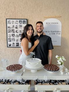 a man and woman standing in front of a table with desserts on top of it