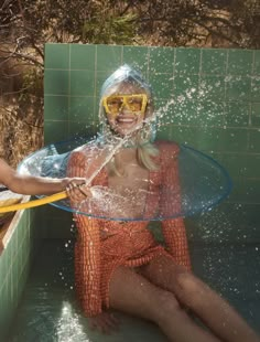 two women in bathing suits and goggles splashing with water