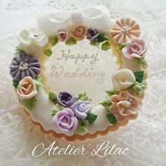 a cake decorated with flowers on top of a white doily covered tablecloth and the words happy wedding written in frosting