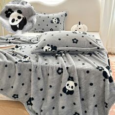 a bed covered in a blanket and pillows with panda bears on it's covers