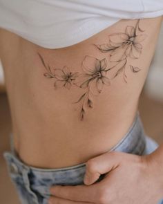 a close up of a person's stomach with flowers tattooed on the side and behind her