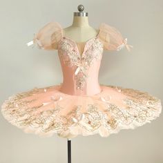 a pink ballet dress on a mannequin with tulle and bows, in front of a white background