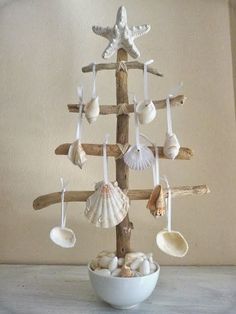 a white bowl filled with seashells on top of a wooden pole in front of a wall