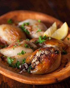 a wooden bowl filled with cooked chicken and garnished with parsley on top