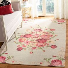 a white rug with pink flowers on it in front of a window and a dresser