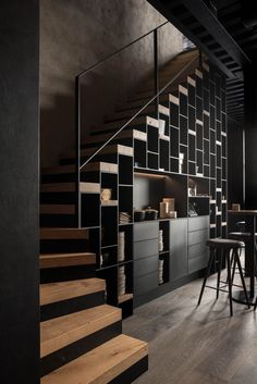 an image of a black and white kitchen with stairs in the center, next to a dining room table