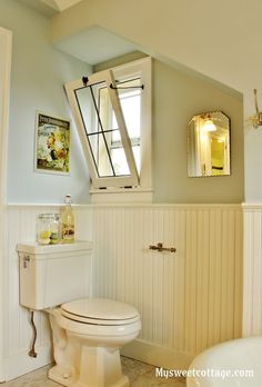 a white toilet sitting under a window in a bathroom